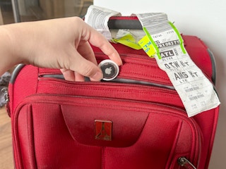 Someone putting an airtag into their suitcase to keep track of it