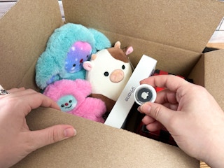 Someone putting an airtag into a package of gifts