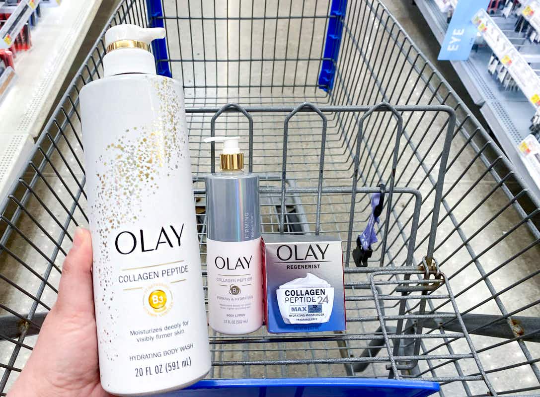 person holding olay collagen peptide body wash alongside other olay products in walmart cart