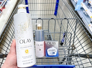 person holding olay collagen peptide body wash alongside other olay products in walmart cart