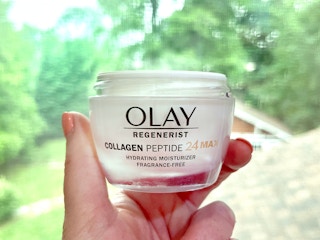 person holding olay regenerist collagen peptide 24 hydrating moisturizer near window