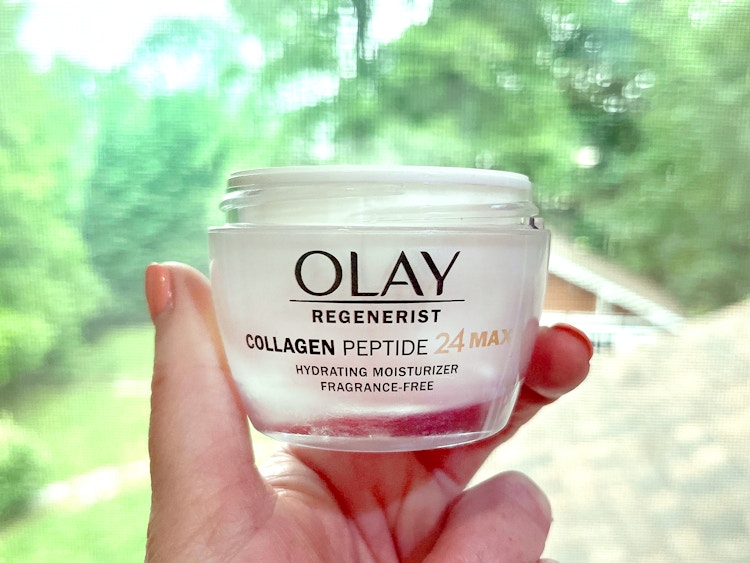 person holding olay regenerist collagen peptide 24 hydrating moisturizer near window