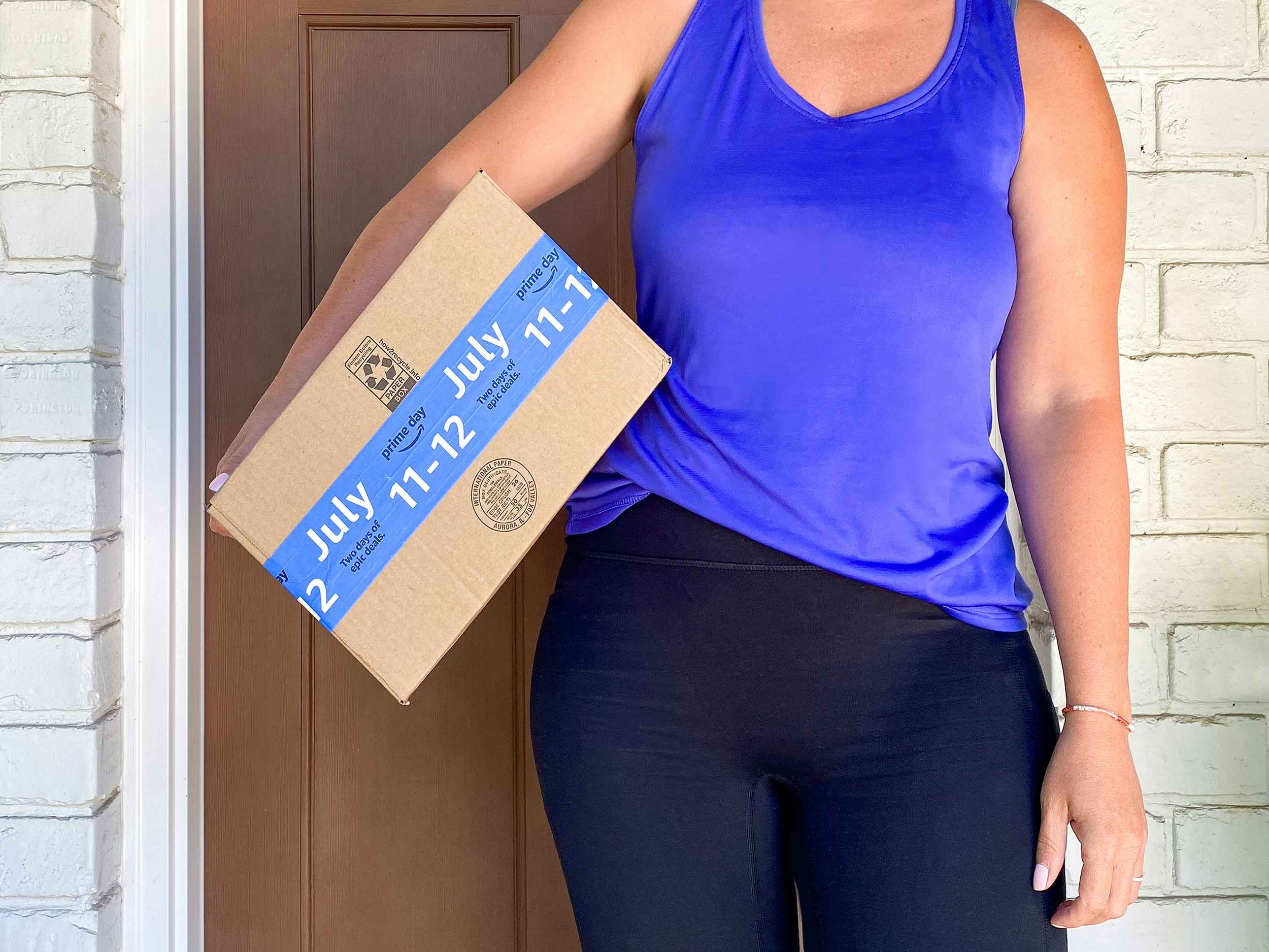 person holding amazon box on front porch with prime day tape for july 11-12