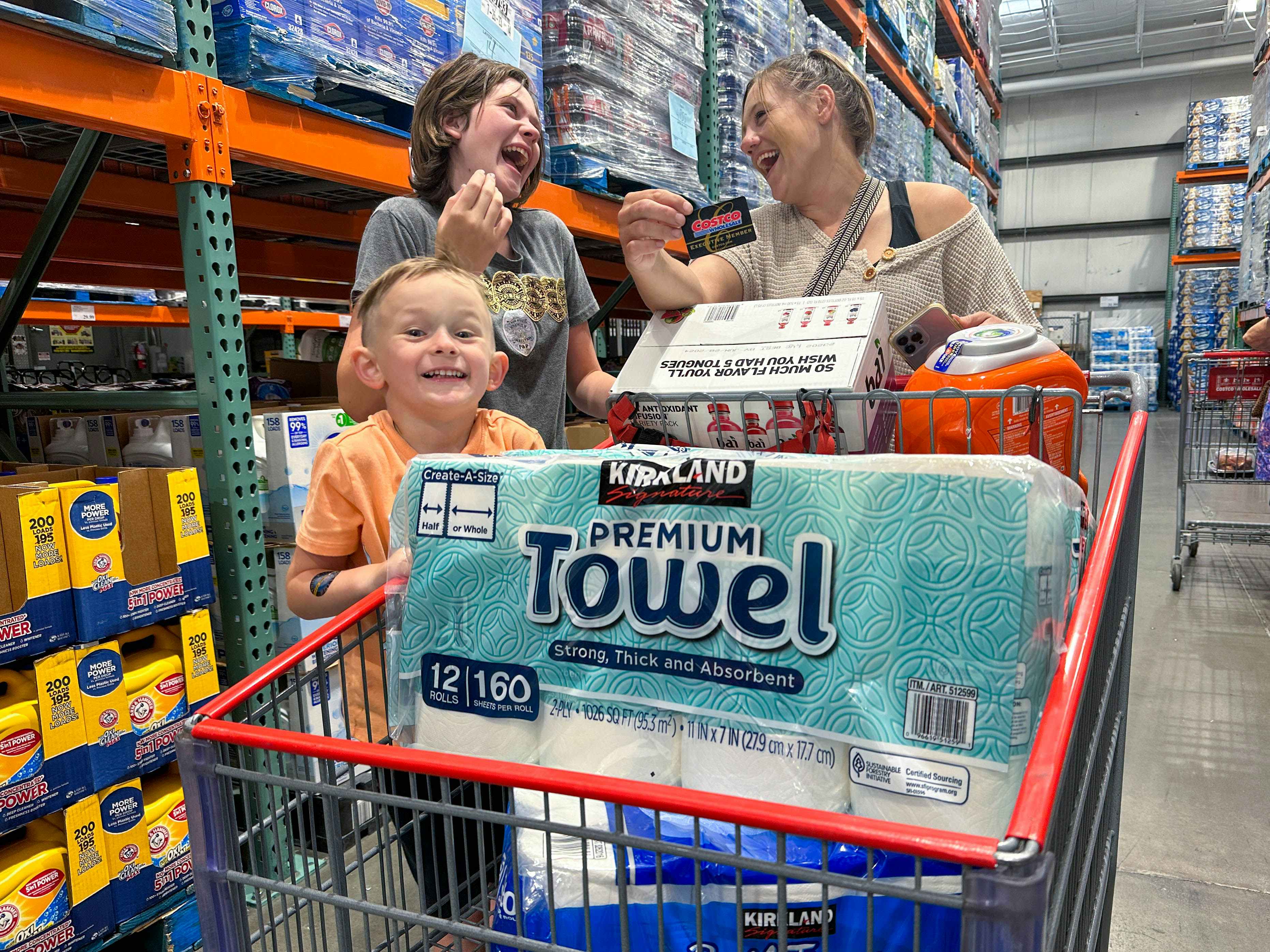 a mother and two kids shopping in costco with a full cart
