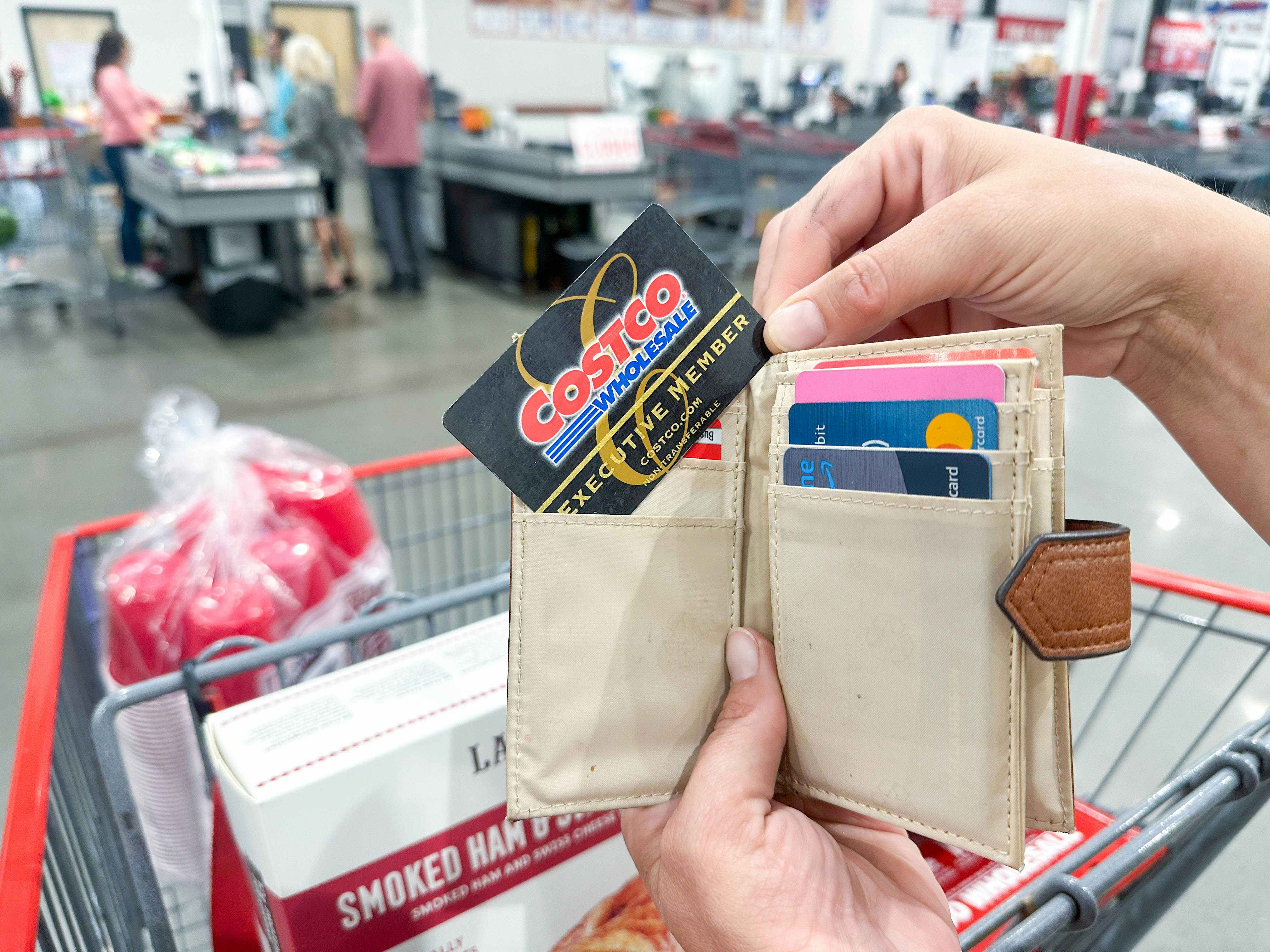 a person holding up a costco card out of wallet at checkout
