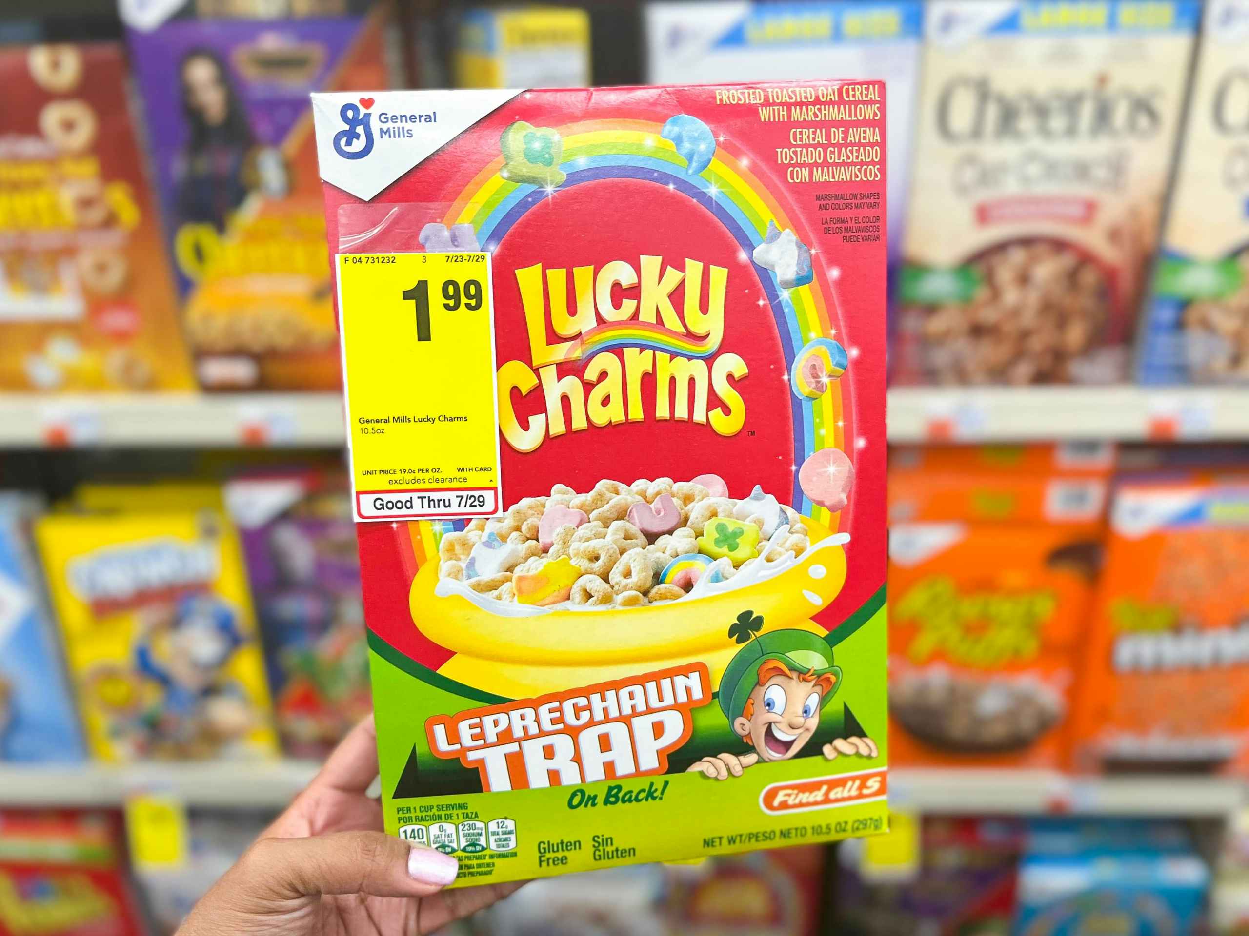 hand holding up box of Lucky Charms cereal with sales tag attached to box in front of display