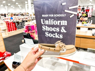 a person holding up a kids sperry shoe in DSW