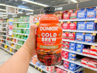 a hand holding up dunkin pumpkin spice cold brew