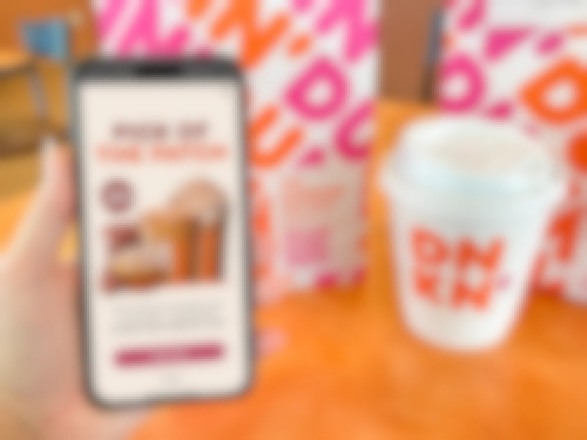 someone holding a phone displaying a Dunkin ad for the new Pumpkin Spice menu