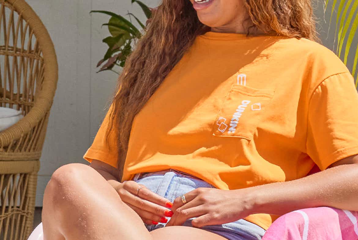 A person wearing an orange crop top from Dunkin'