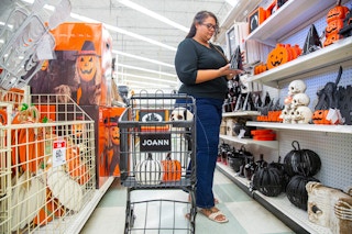 Person shopping for Halloween deecor with a Joann's shopping cart with decor inside of it