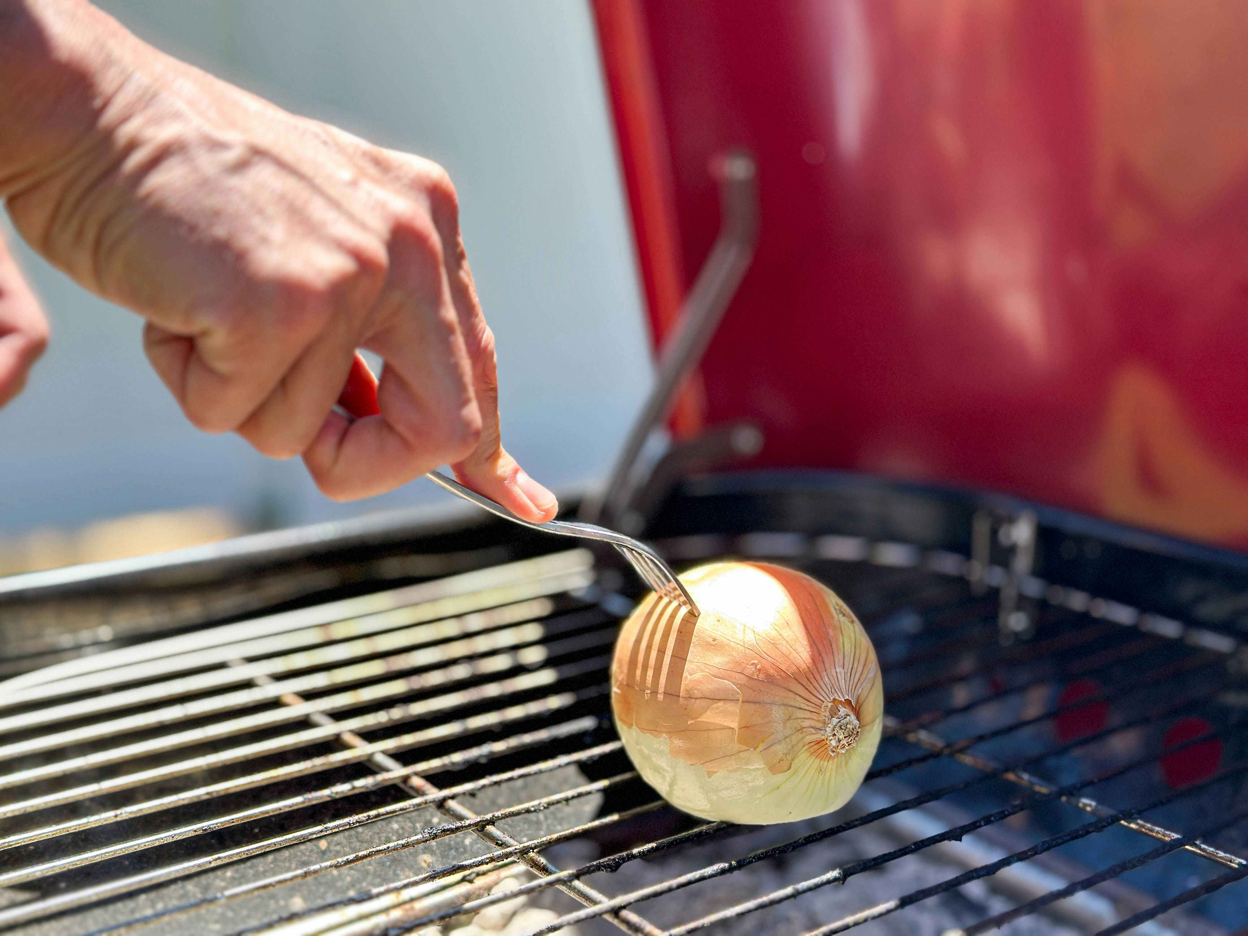 an onion being pushed on a grill with a fork 