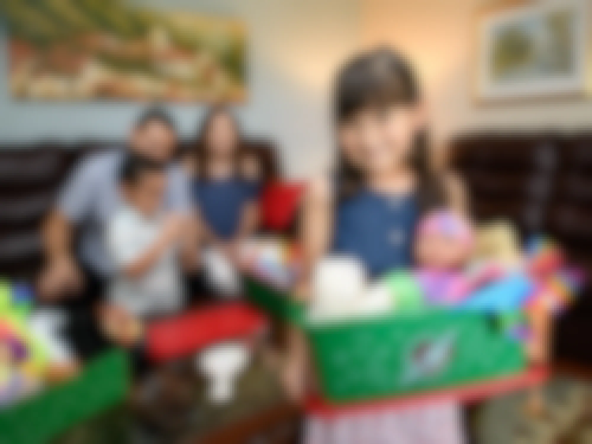 A child opening up a gift box from Operation Christmas Child in a living room with her family