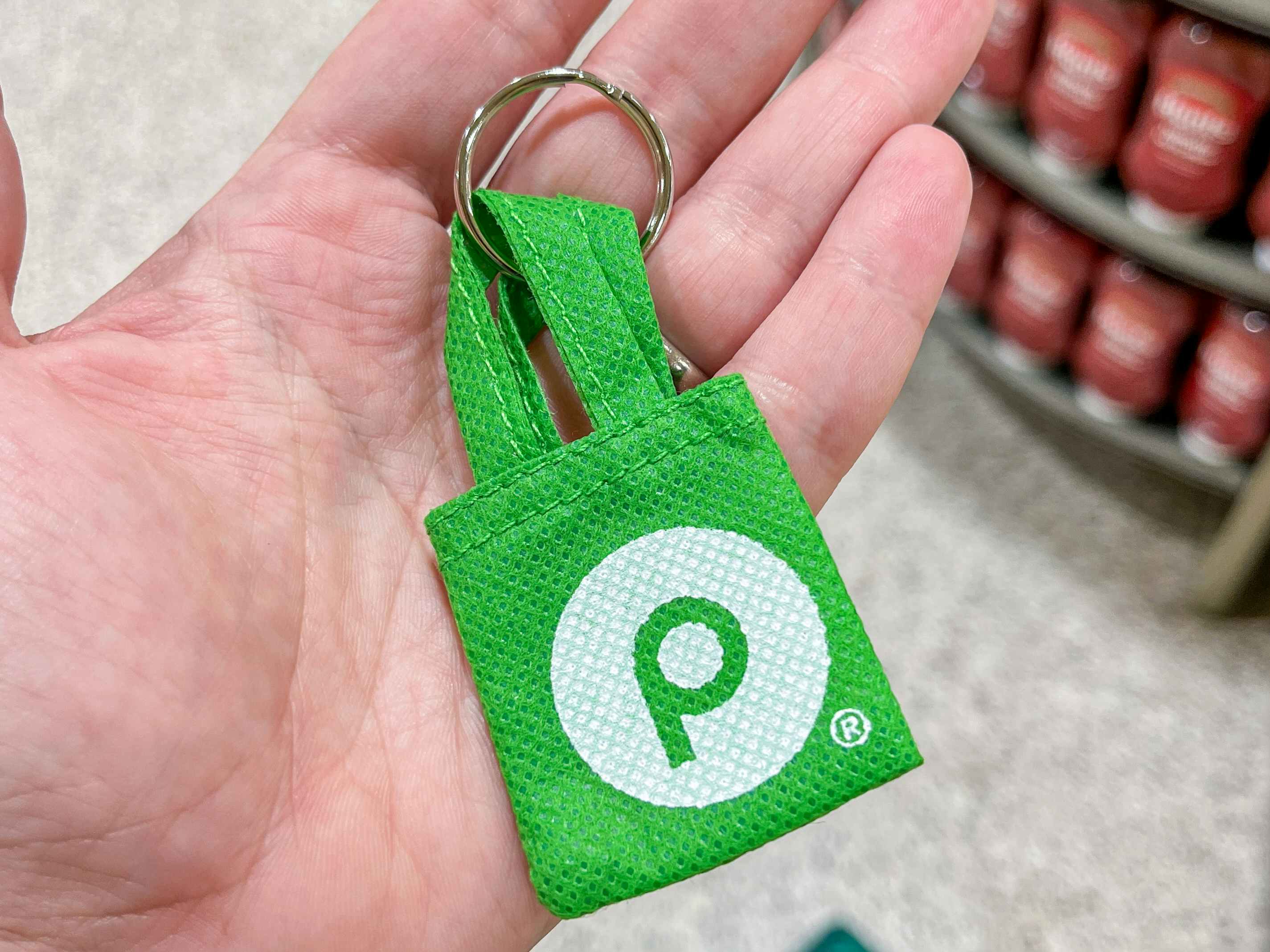 a person holding up a mini reusable bag keychain 