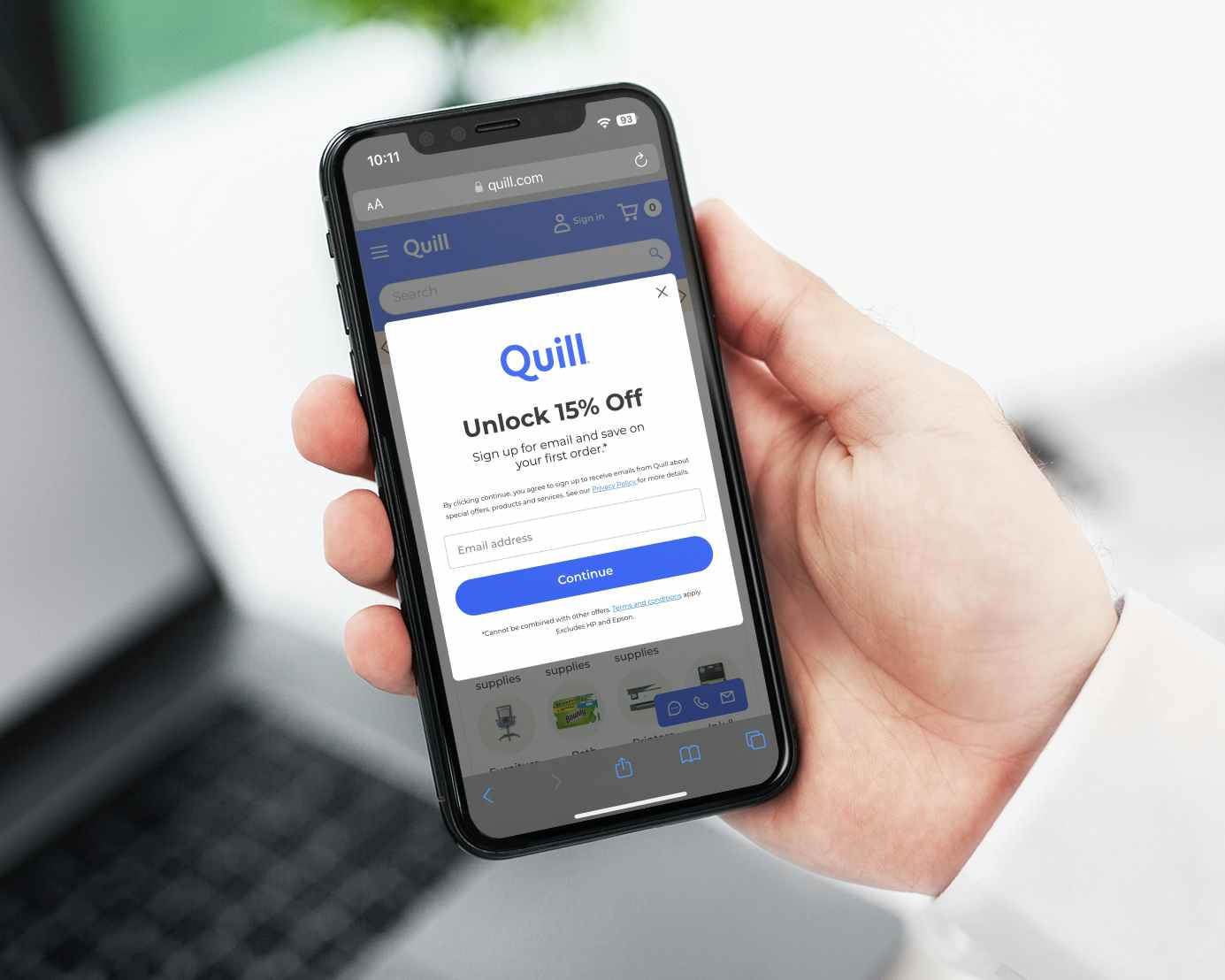 A person holding a phone displaying the email sign up offer for 15% off on Quill.com