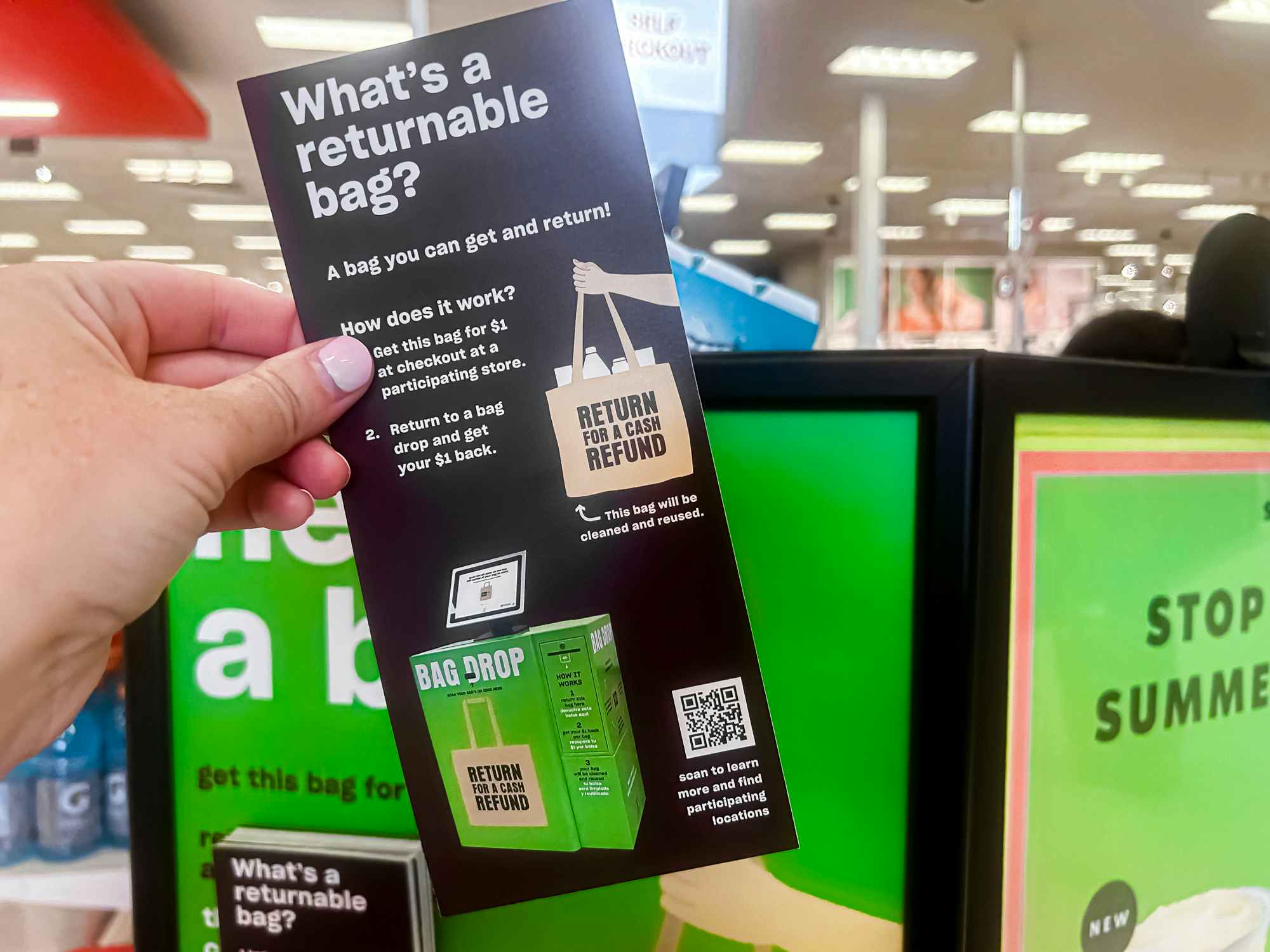 Someone holding up a returnable bag brochure next to a sign in Target