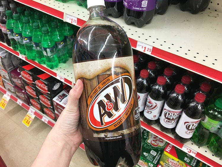 a hand holding up an A & W two liter 