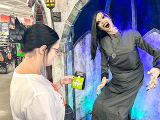 a person looking at the price tag of a spirit halloween animatronic