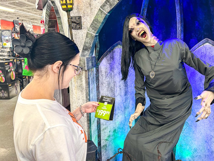 a person looking at the price tag of a spirit halloween animatronic 