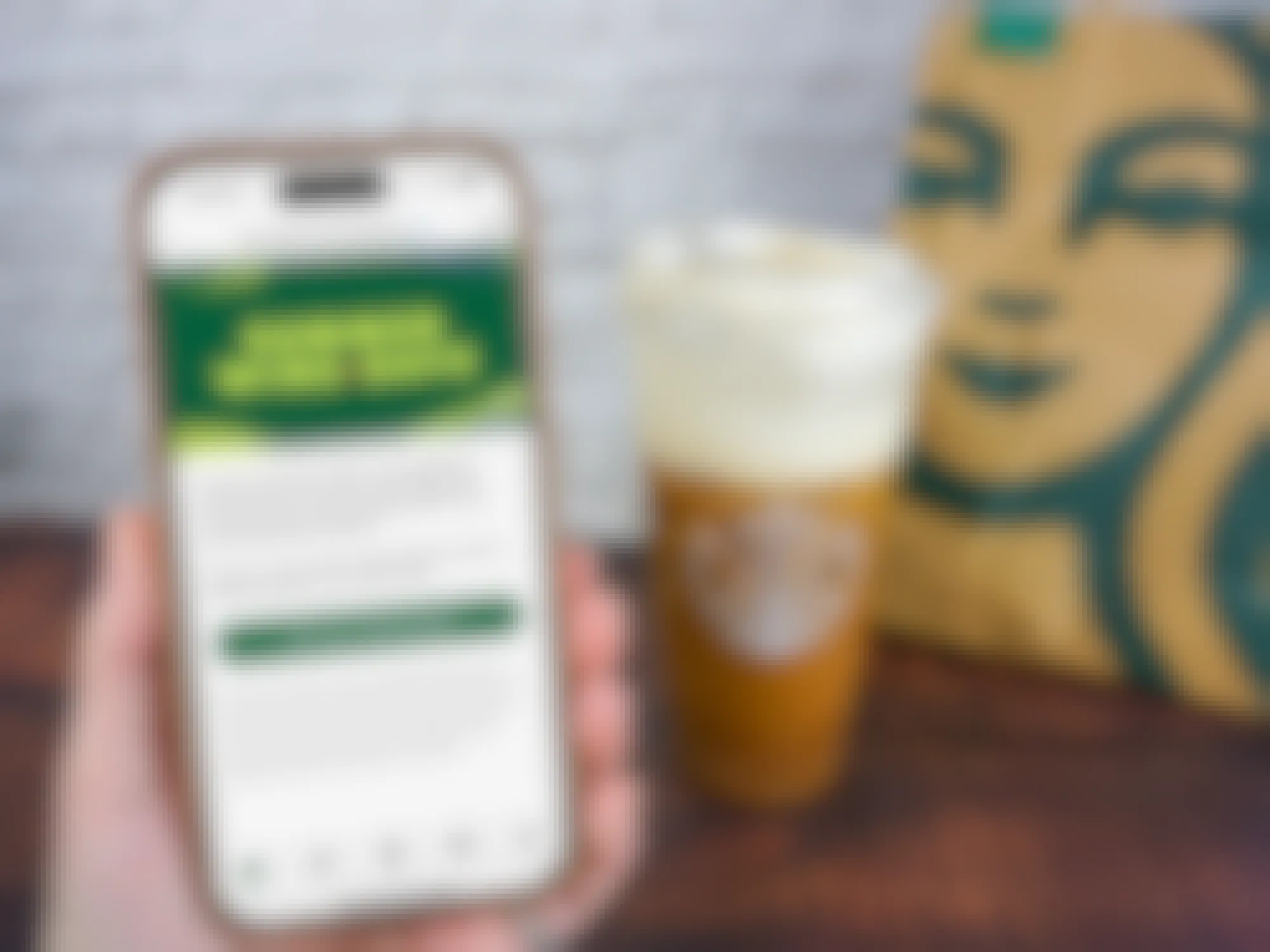 Someone holding up a phone displaying the Starbucks app offer for 50% off of cold drinks on certain days