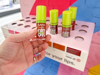 Someone picking out a shade of Nyx Fat Lip Drip Oil