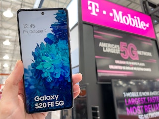 Someone holding up an android phone in front of a T-Mobile sign