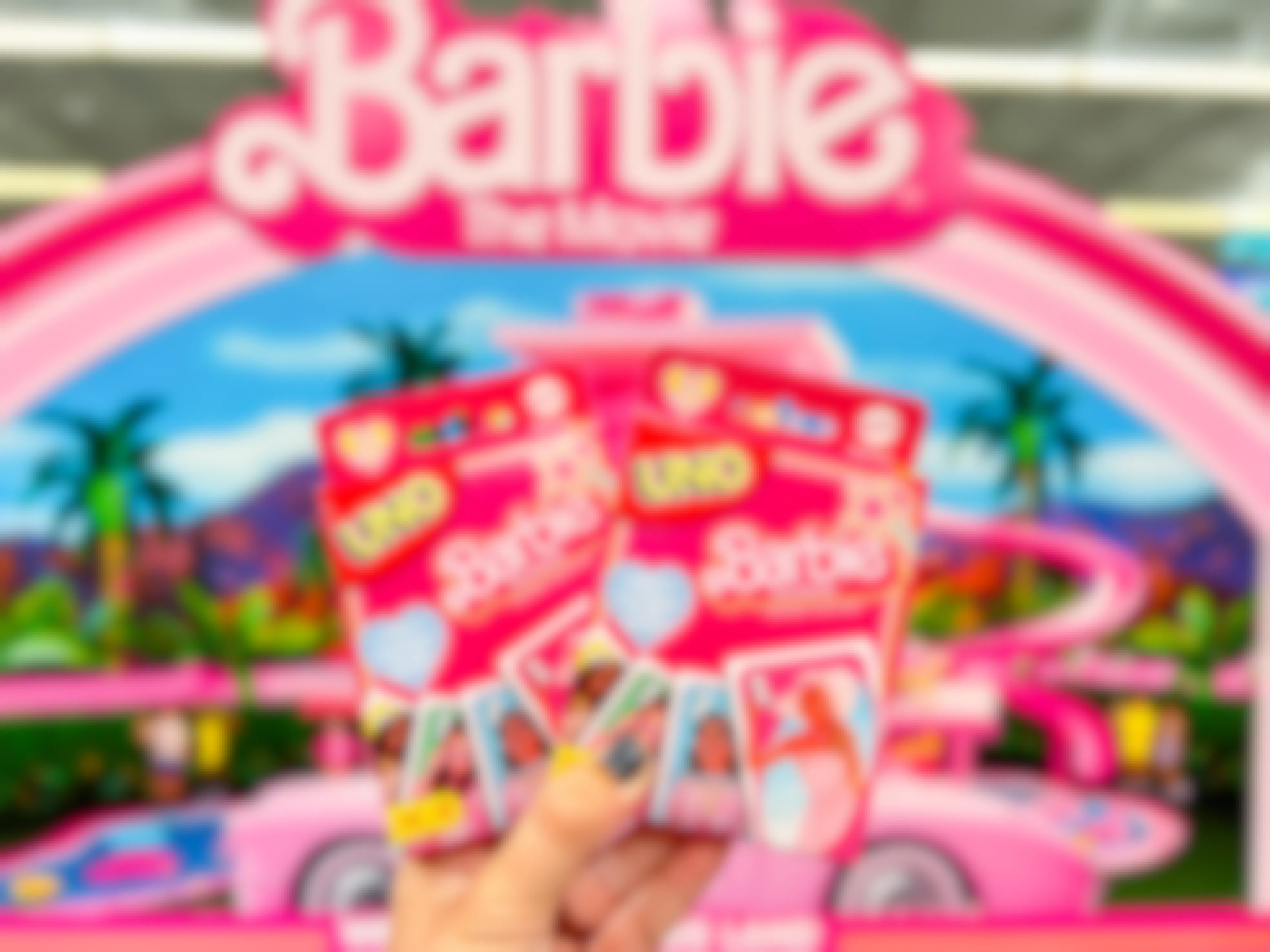 a hand holding barbie uno card game boxes