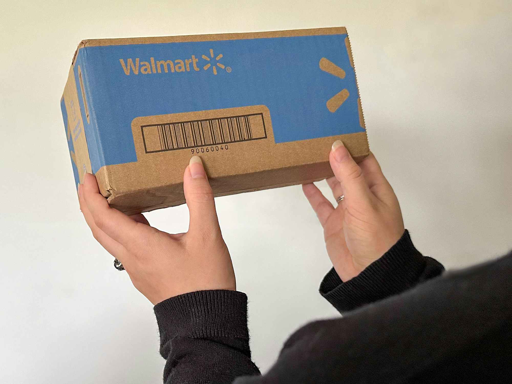 Someone holding up a box shipped from Walmart.com