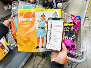 a person comparing prices on costumes in walmart vs amazon in store