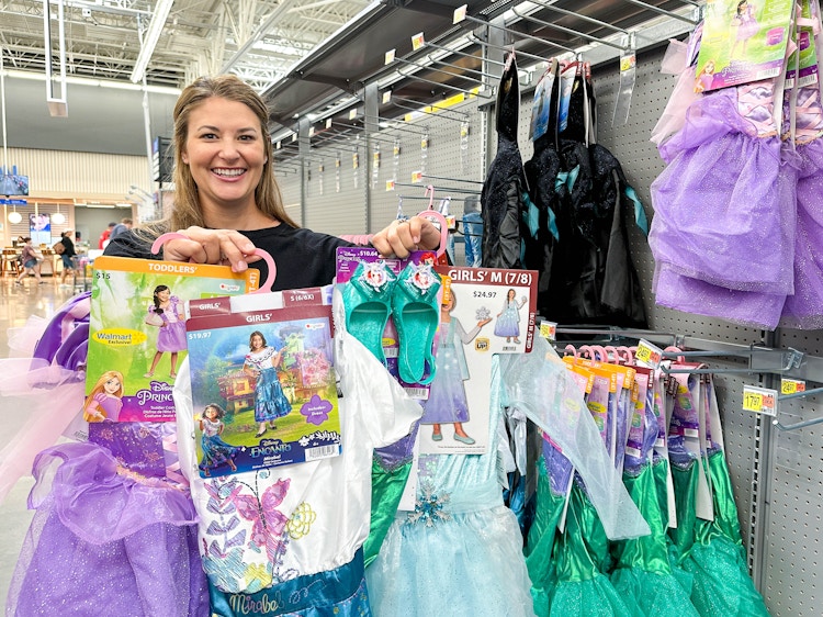 a person holding up disney costumes in walmart 