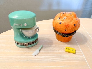 Two porcelain hinged boxes with their trinkets on the table next to them