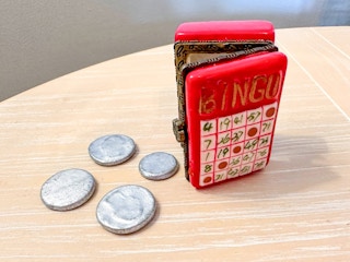 A porcelain hinged box with its trinkets on the table next to it