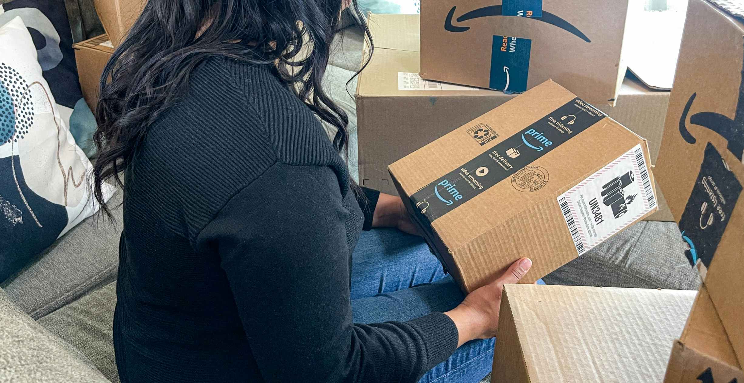 a person sitting on their couch holding an amazon box