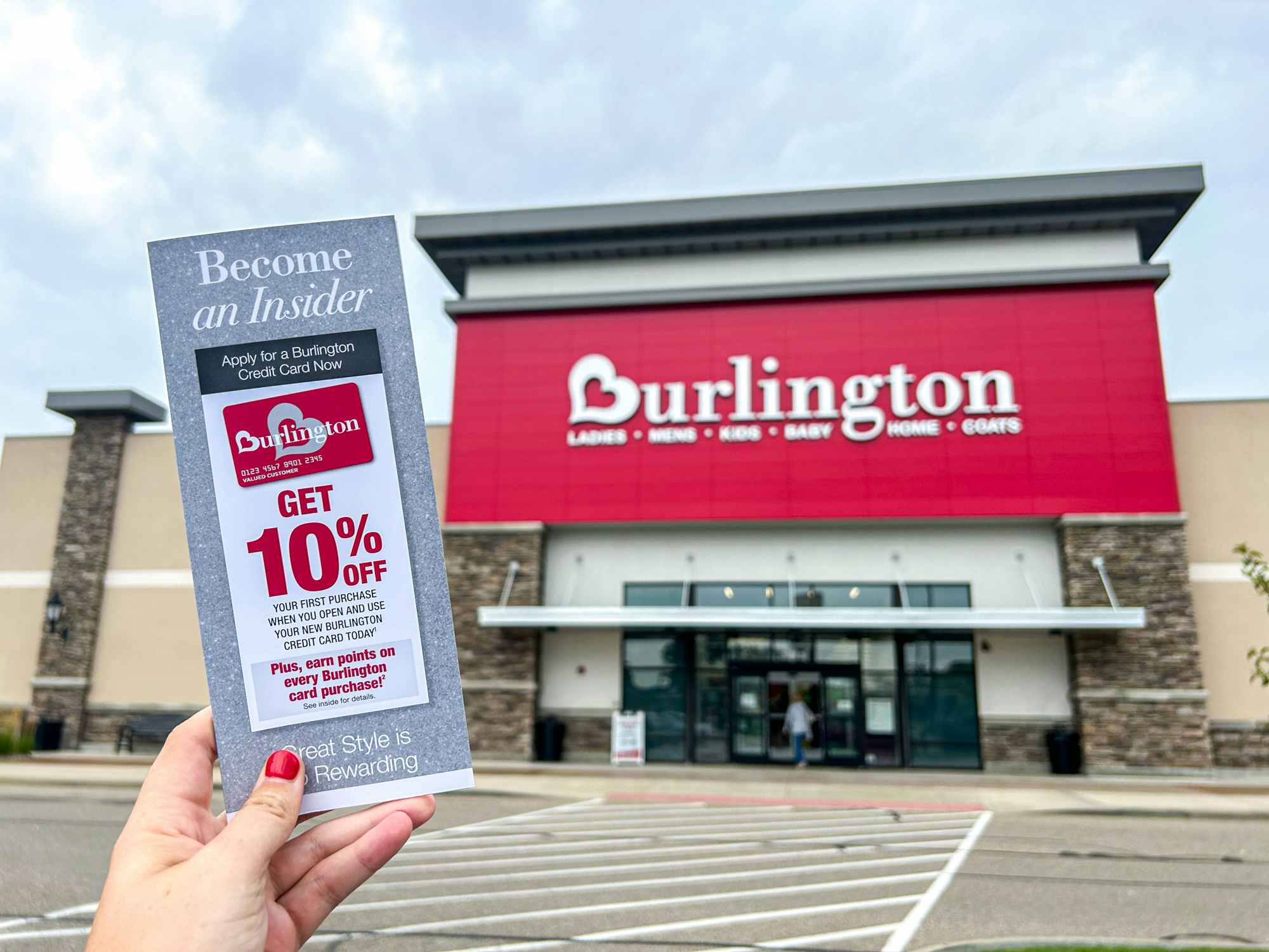 a person holding up a burlington credit card pamphlet in front of a burlington store 