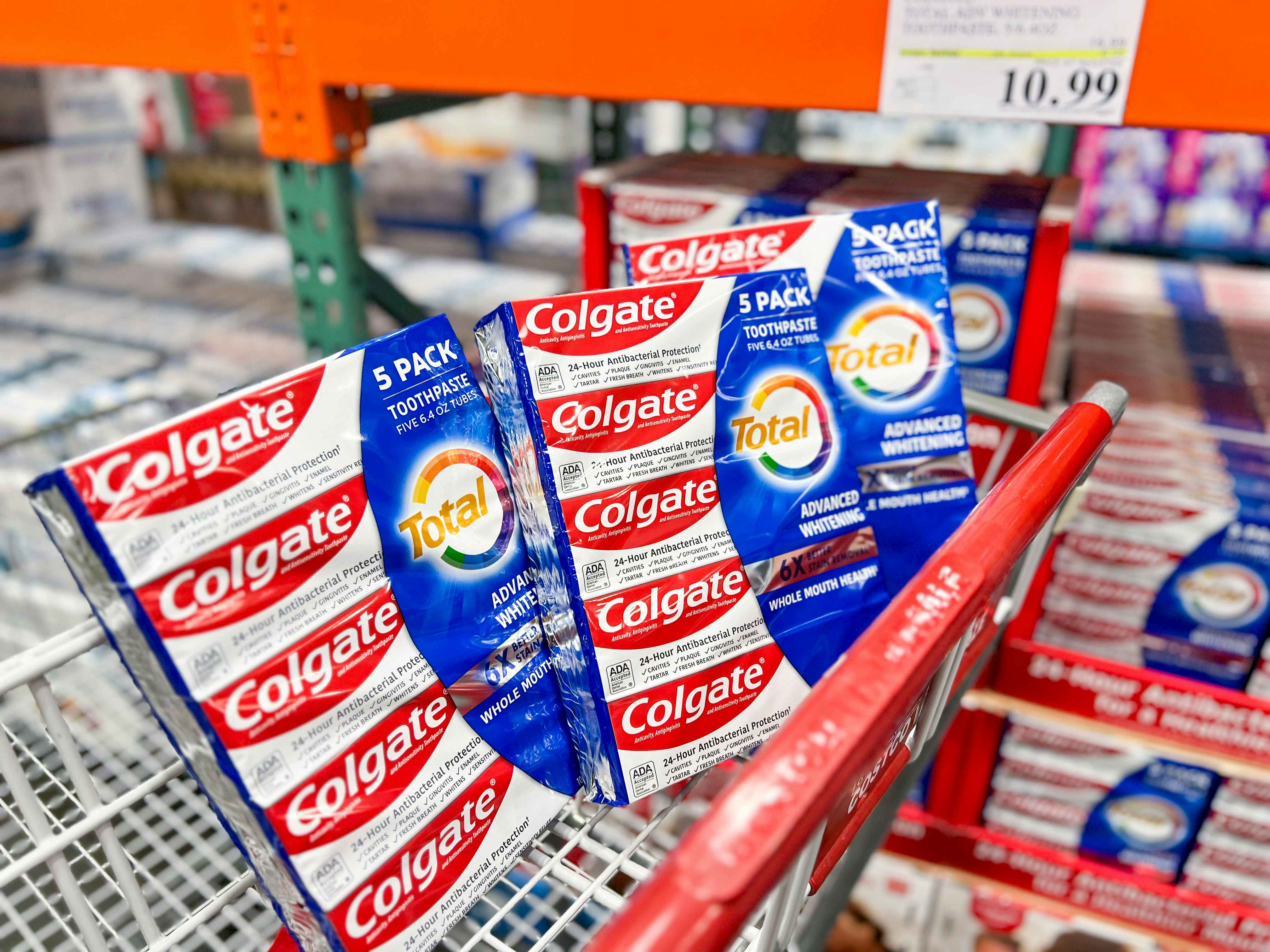 a three pack of colgate toothpaste in a costco cart