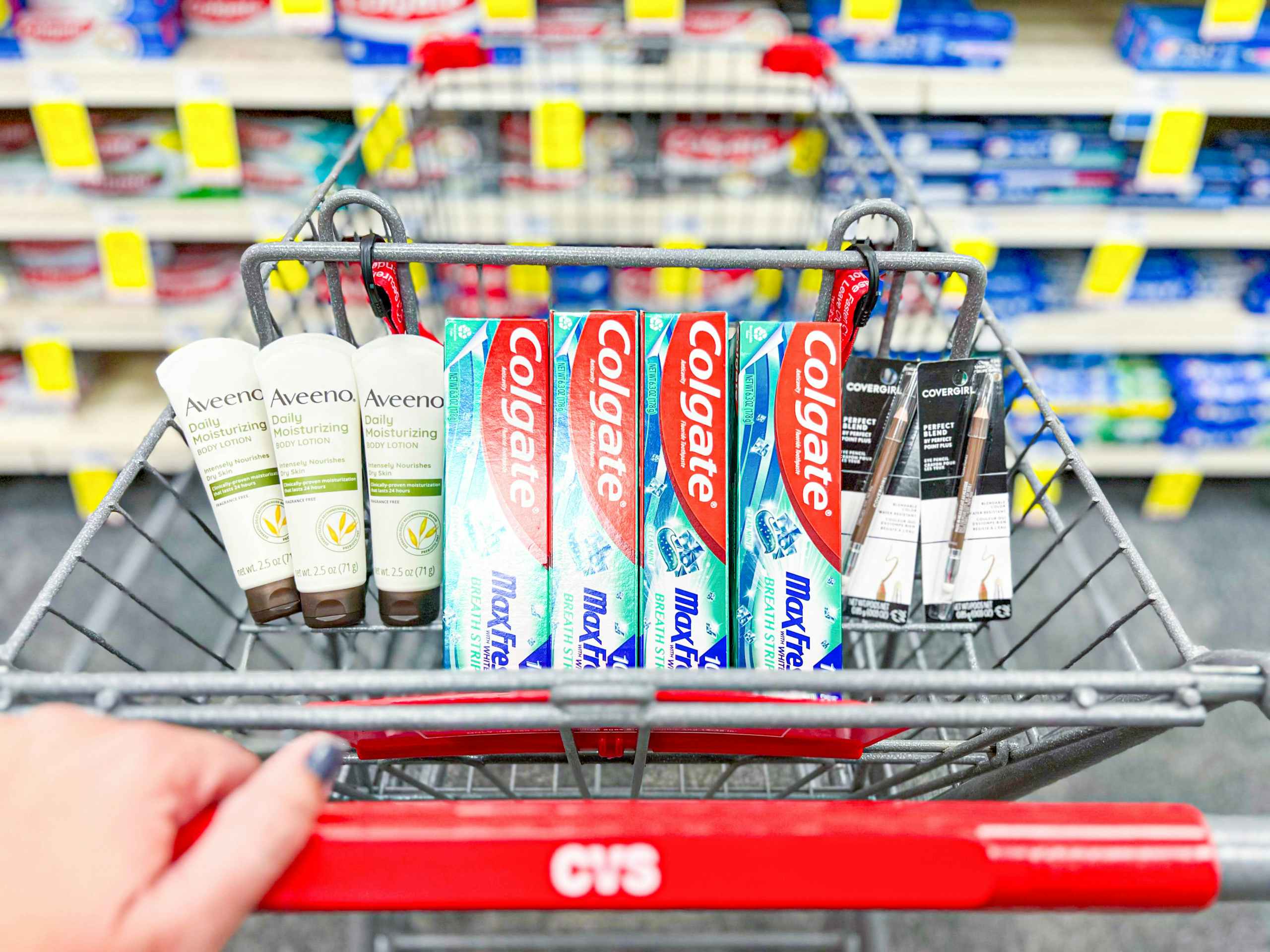 cvs shopping cart with four Colgate toothpaste, three Aveeno lotions, and two Covergirl eye pencils inside