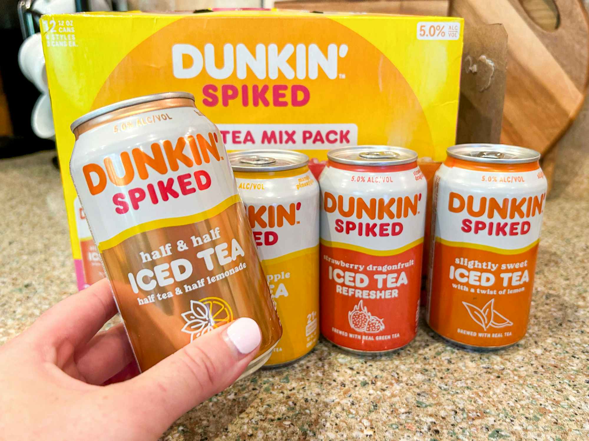 a case of Dunkin Spiked iced tea on a counter with someone holding a can