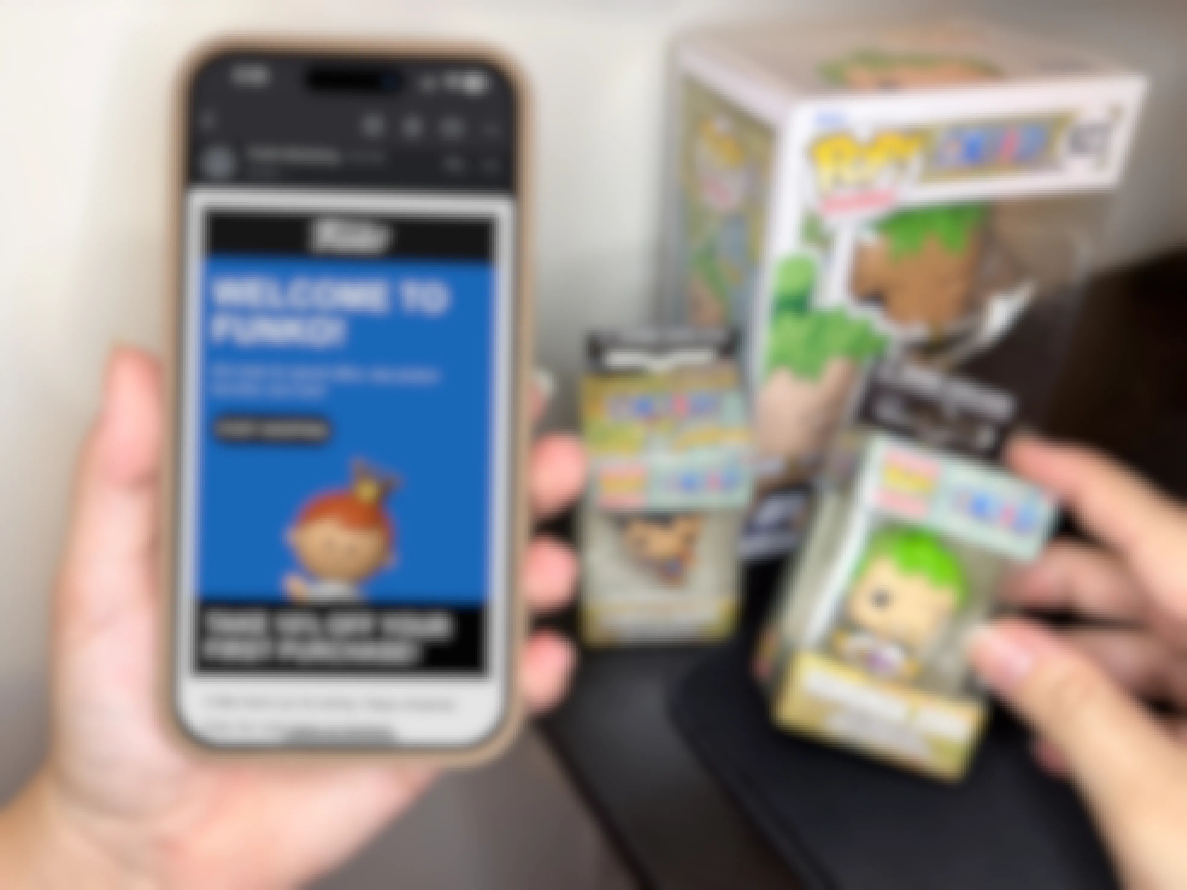 someone holding up a phone displaying a coupon for the Funko website next to some Funko POP Vinyls