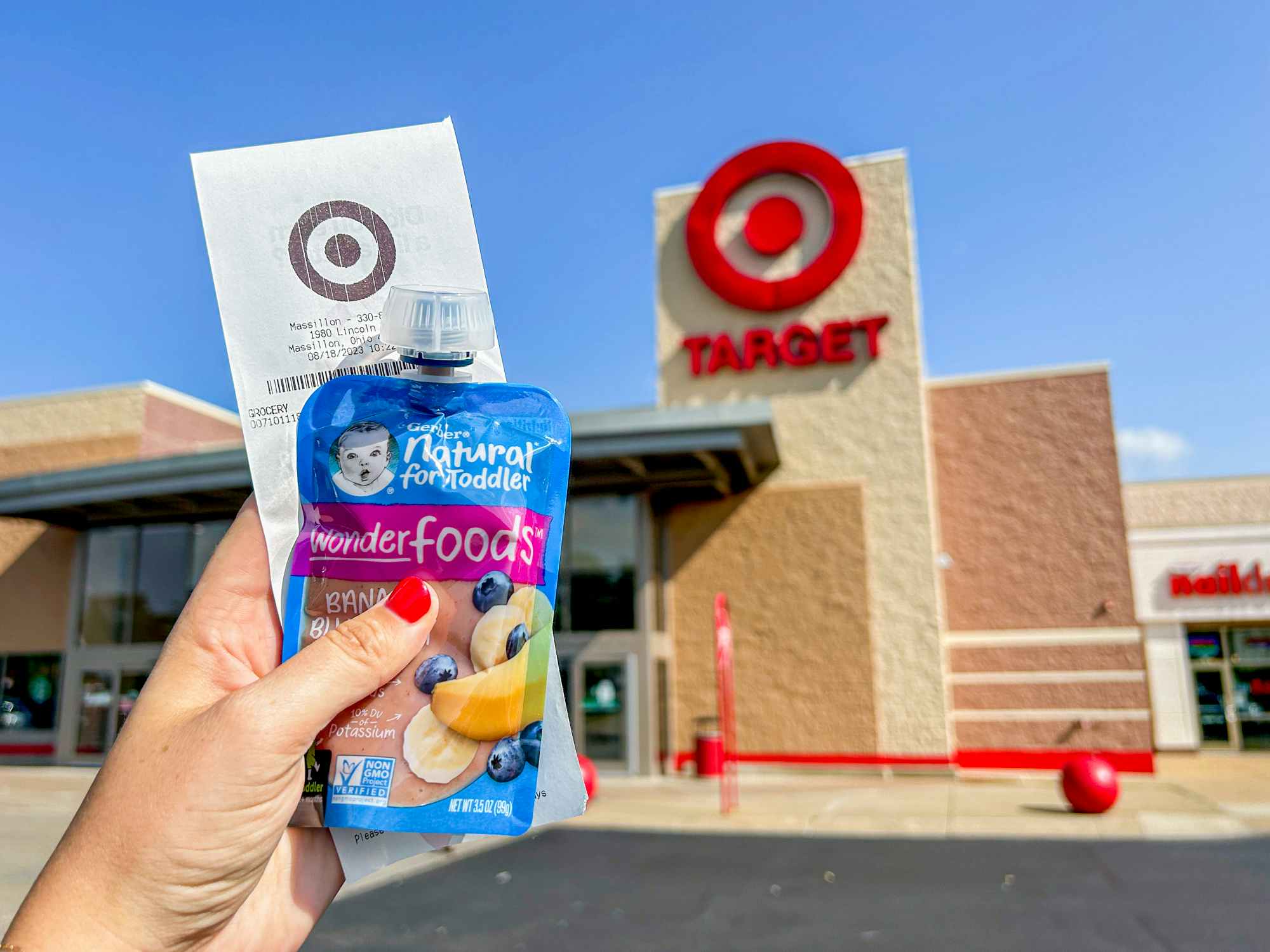 a person holding up gerber baby food with a receipt in front of the target sign