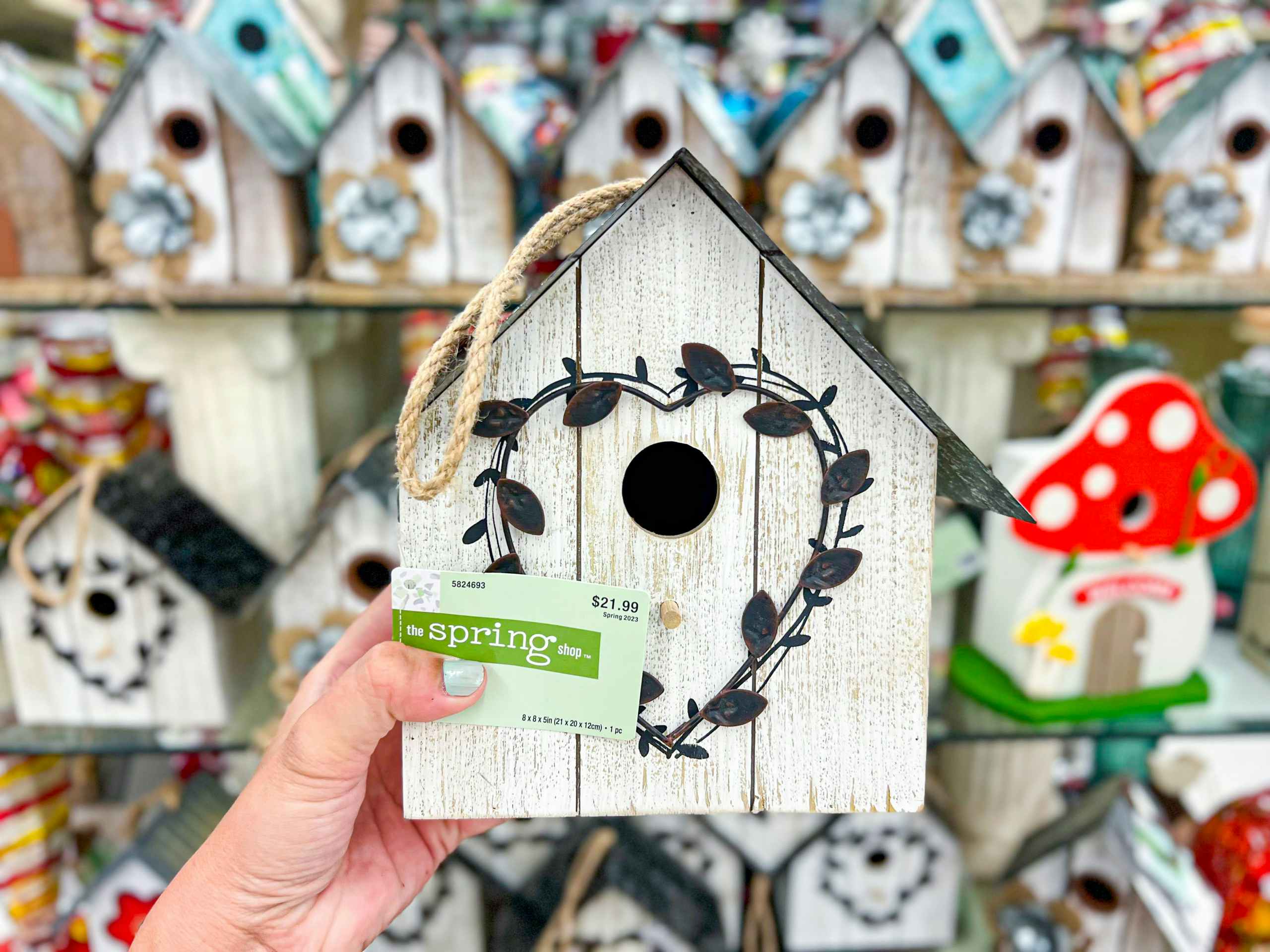 hand holding up a wooden bird house
