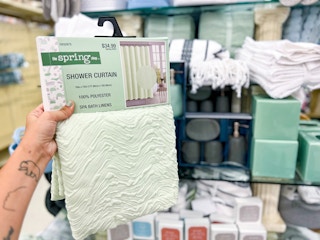 hand holding up a mint green shower curtain