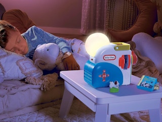 a child sleeping next to a Little Tikes Story Dream Machine projector