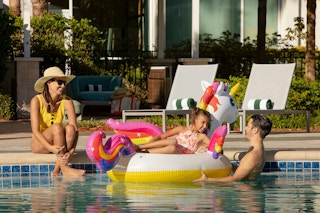 A family together at the pool with their child in a pool float