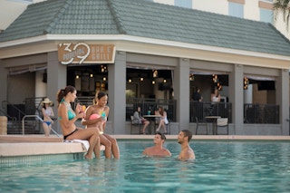 A group of friends hanging out in a pool next to a hotel restaurant