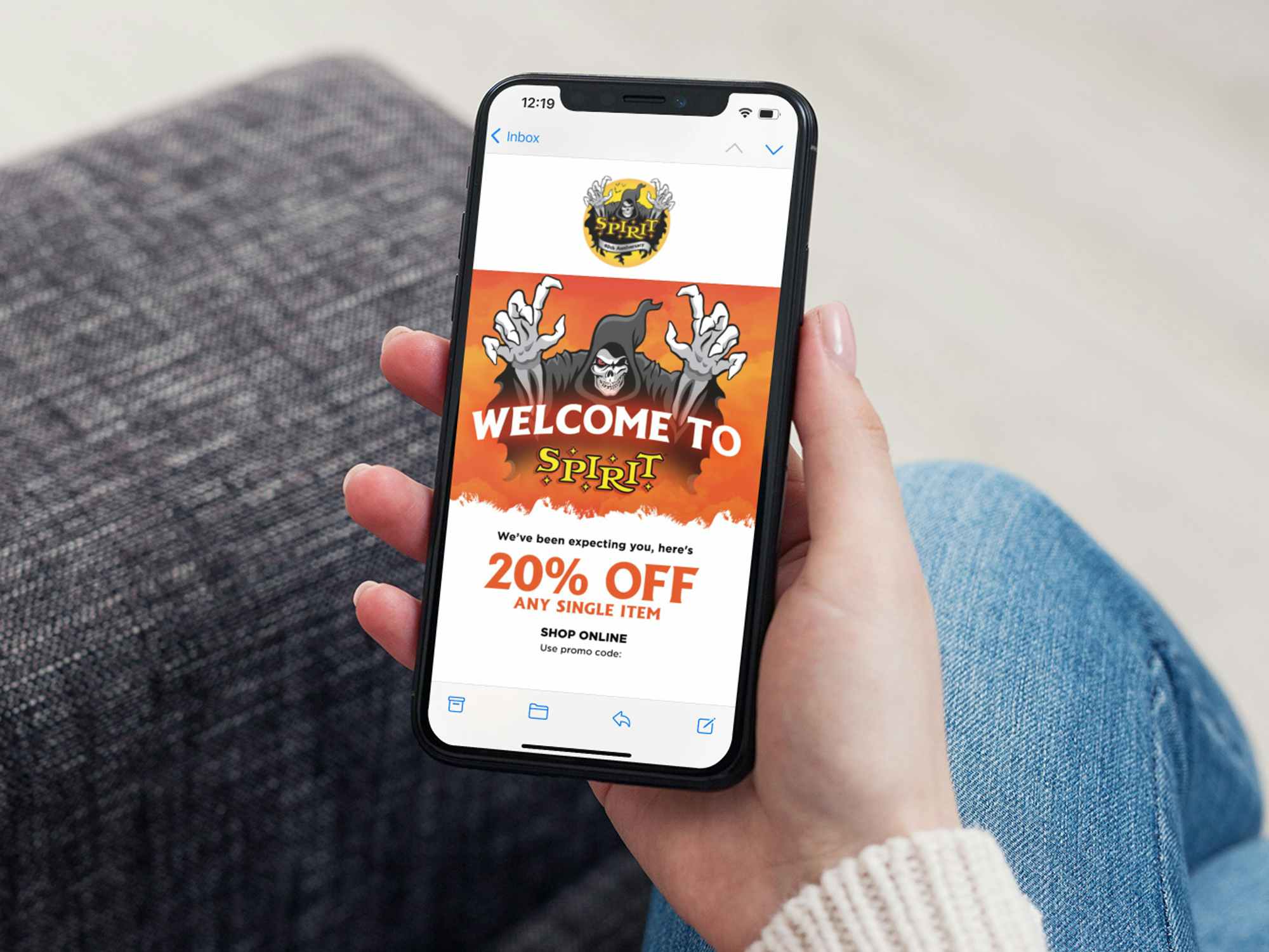 a person holding an iphone with a spirit halloween coupon on it