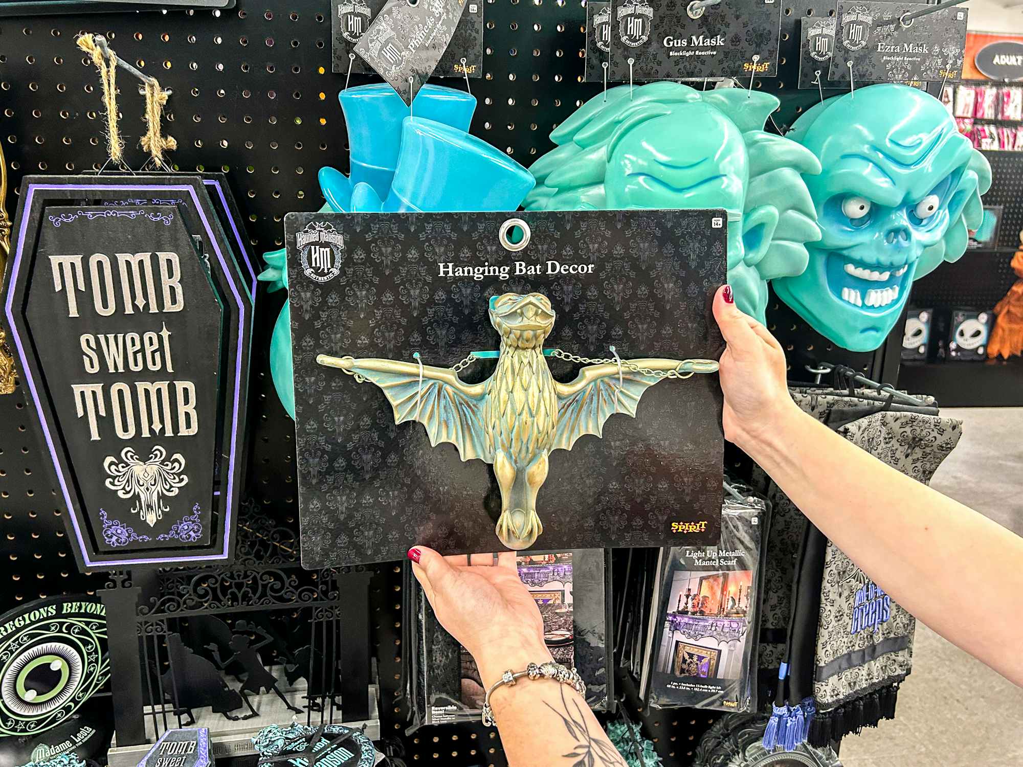 a person holding up a spirit halloween haunted mansion bat