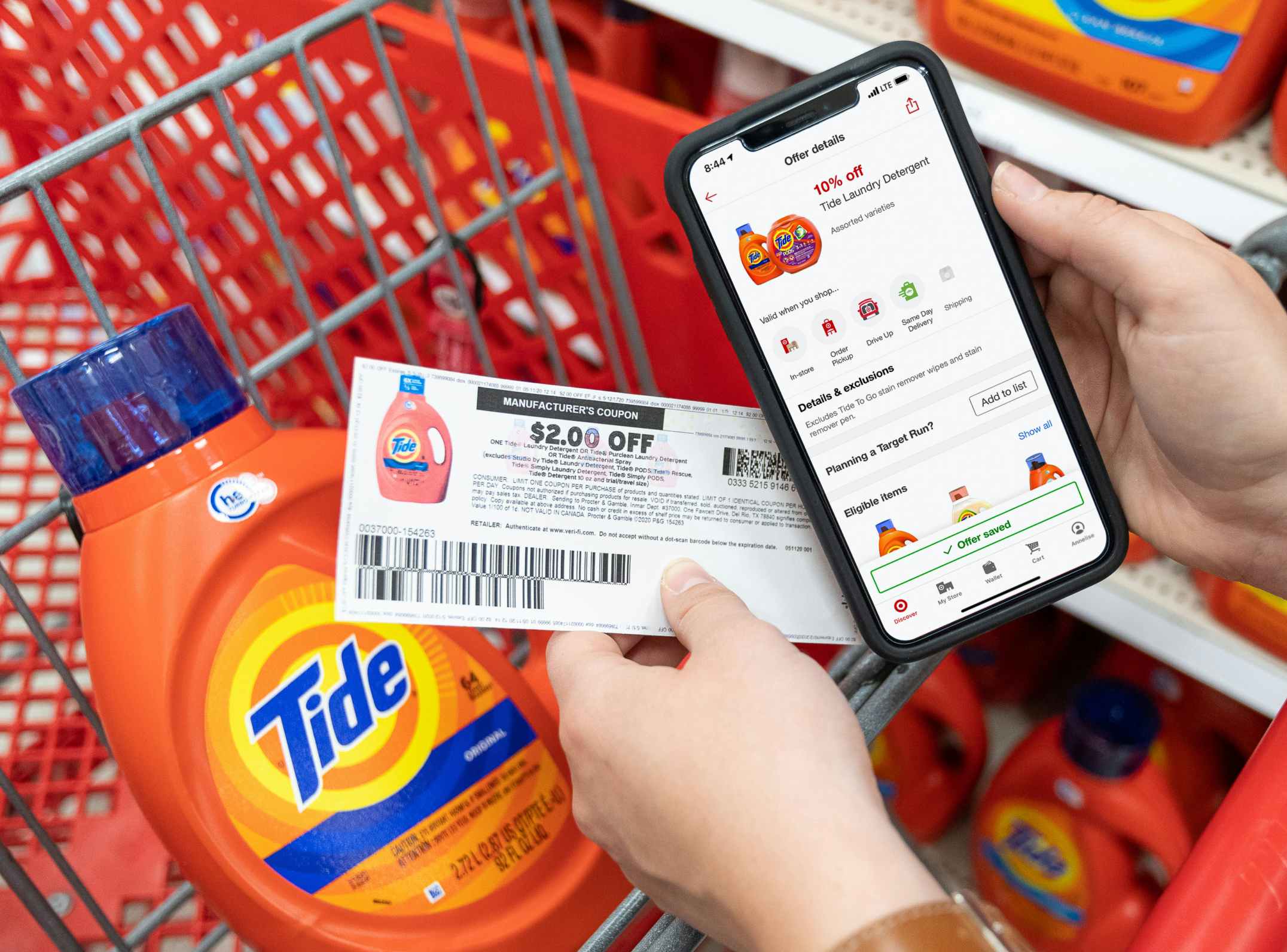 A person's hands holding a cell phone displaying 10% off Tide laundry detergent on the target circle app and a $2 off manufacture coupon, and a bottle of Tide liquid detergent in a Target shopping cart.