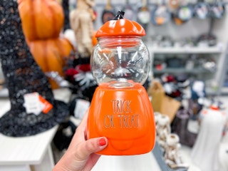 hand holding up a pumpkin decor that says trick or treat