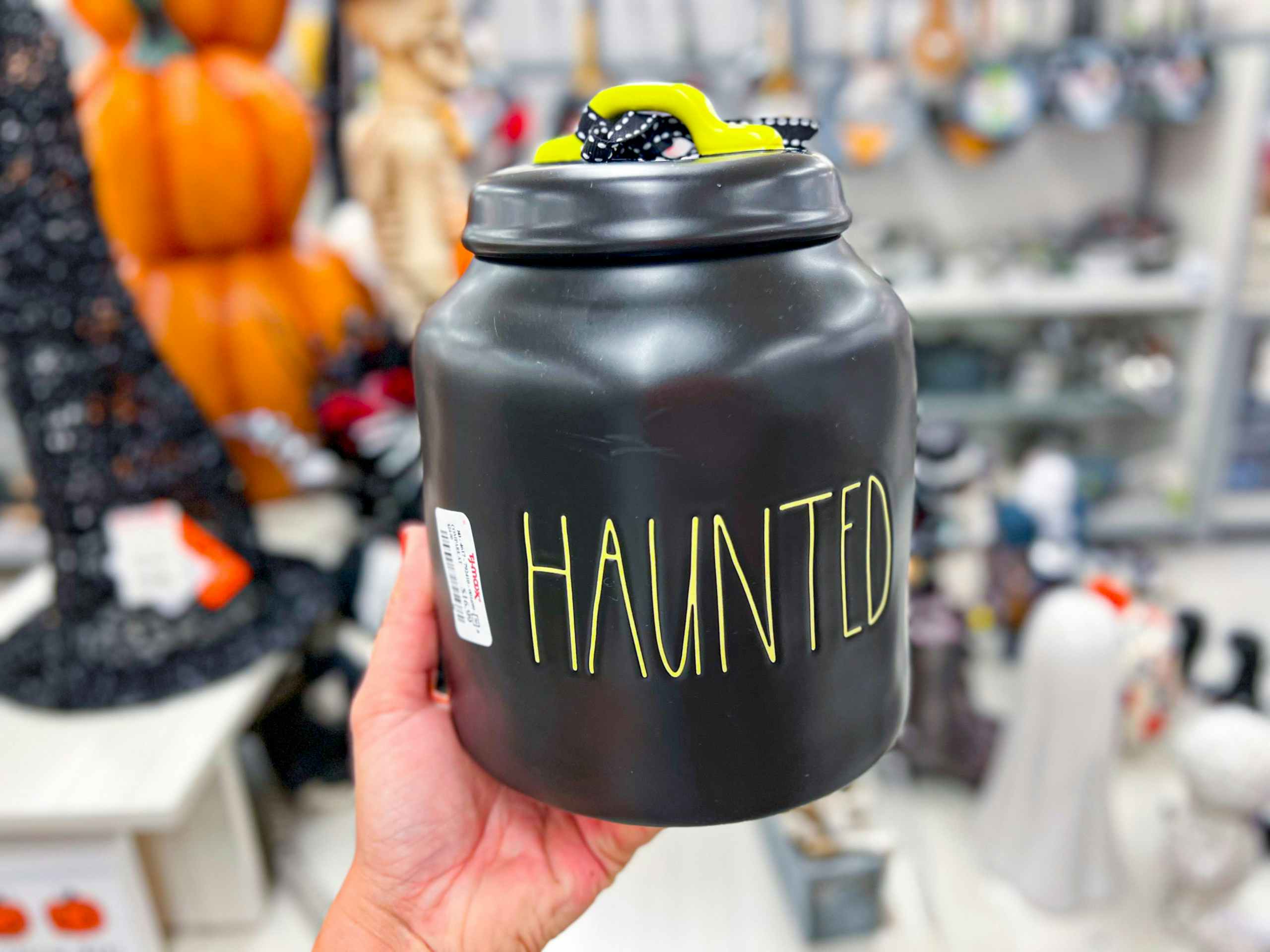 hand holding up a black rae dunn jar that says "haunted