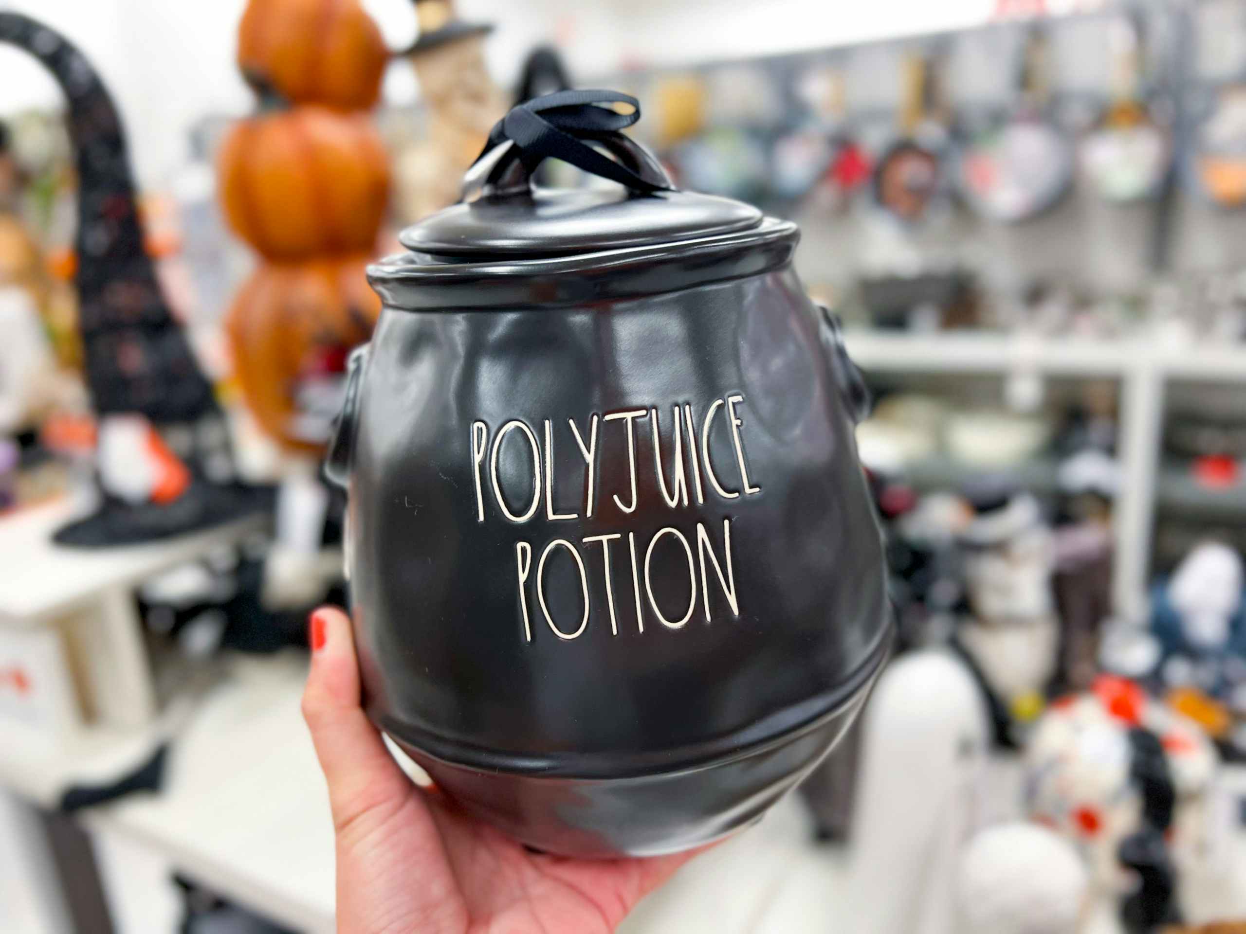 hand holding up a black rae dunn jar that says "polyjuice potion